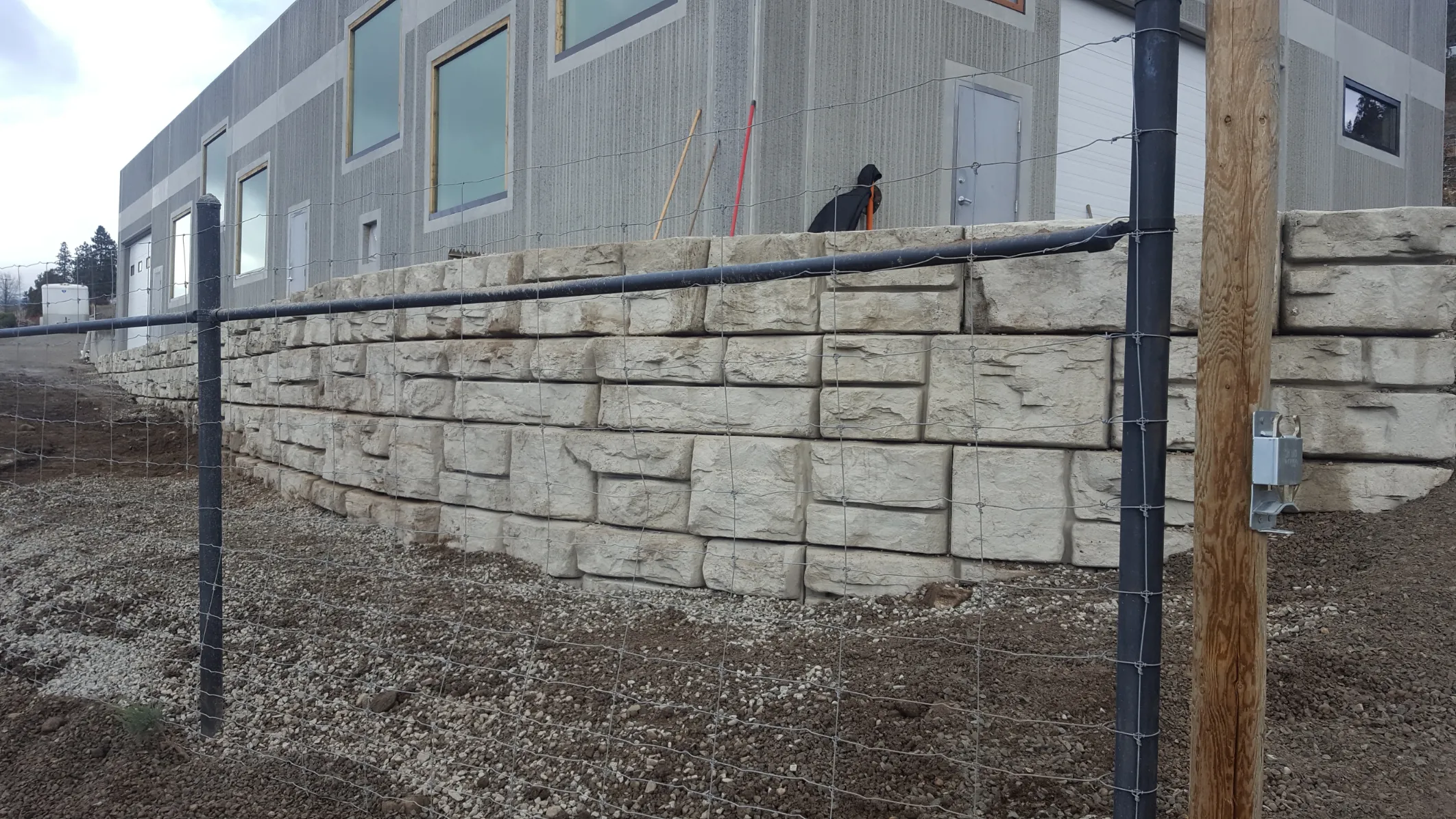 Multi-tiered natural stone retaining wall with decorative boulders and drought-tolerant landscaping in Osoyoos BC